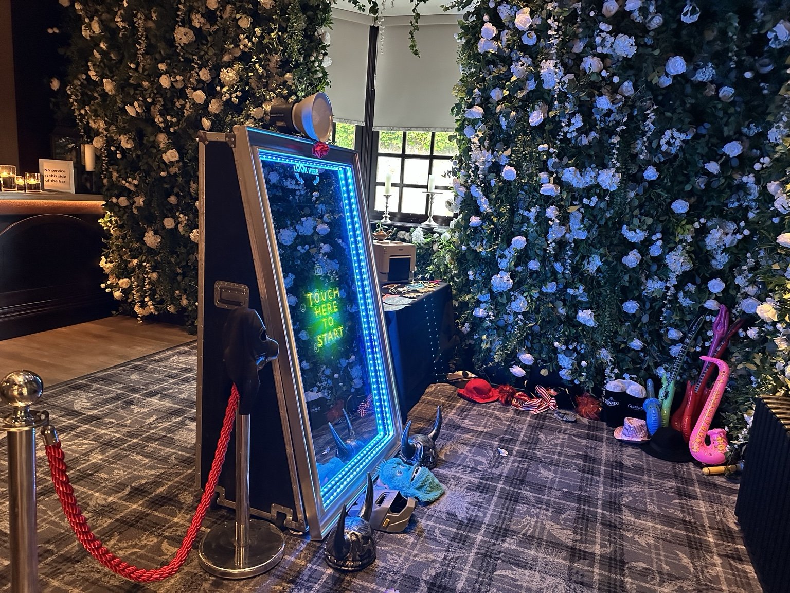 Magic mirror positioned beside a floral wall at an event