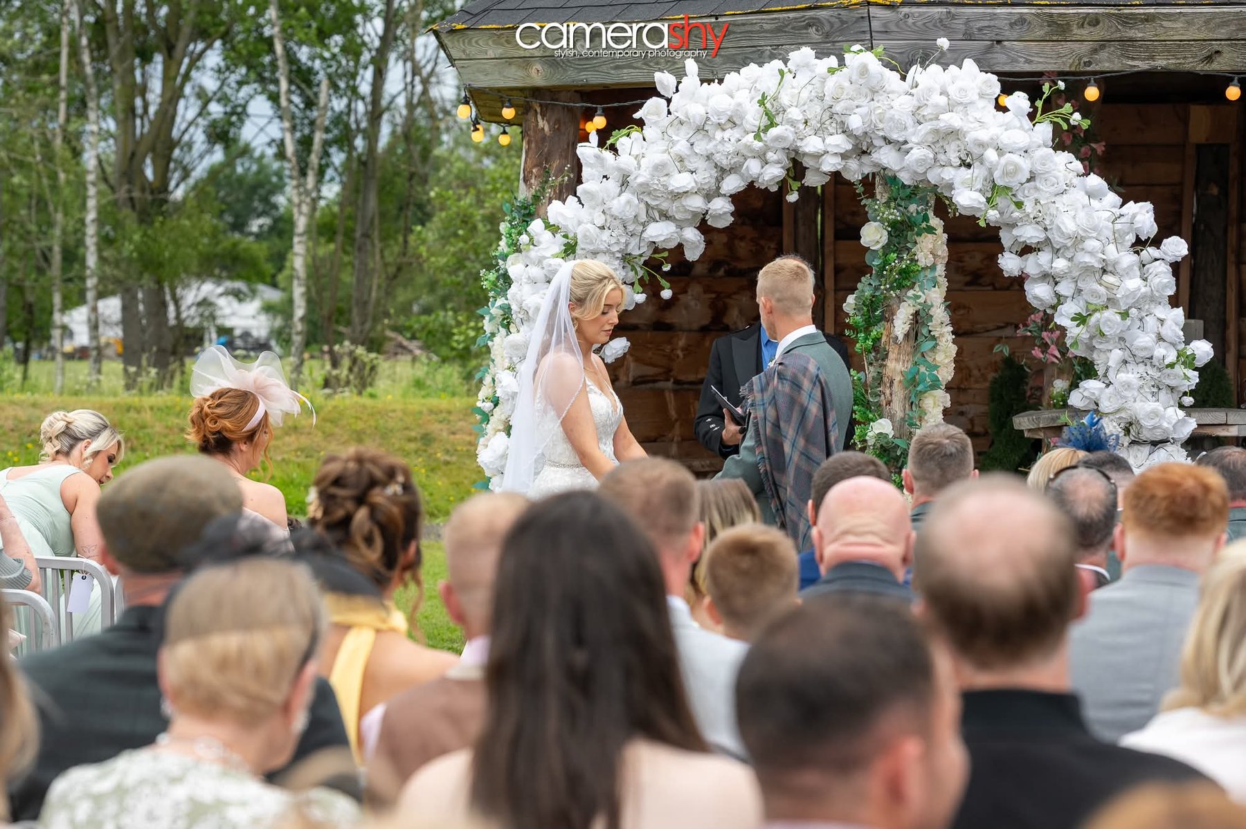 White floral arch at an outdoor wedding ceremony in Scotland
