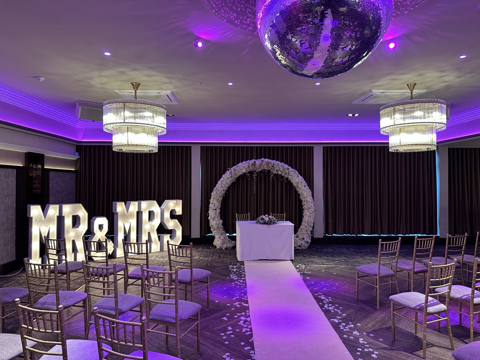 Wedding ceremony setup with floral arch and MR and MRS letters