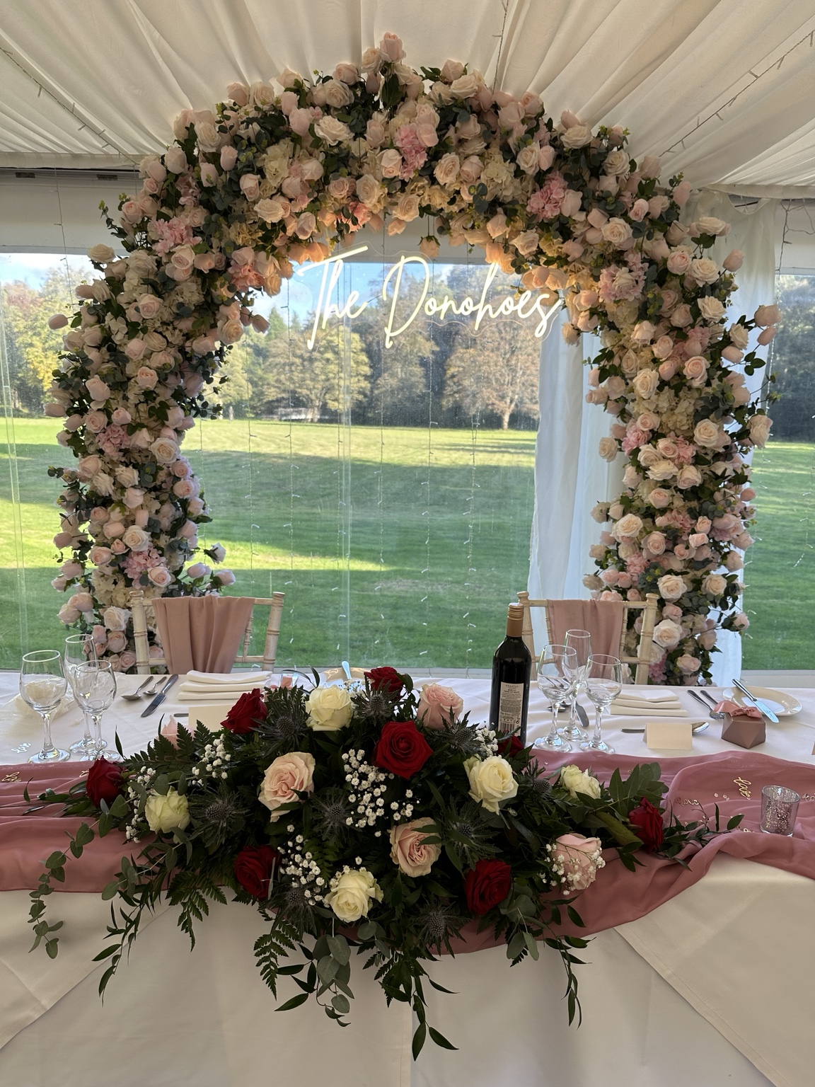 Floral arch with personalised neon surname sign