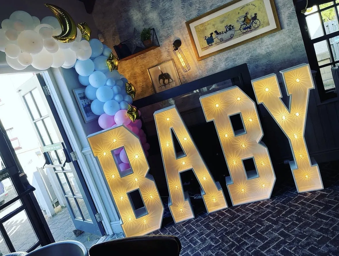 Illuminated BABY letters with balloon styling at a baby shower