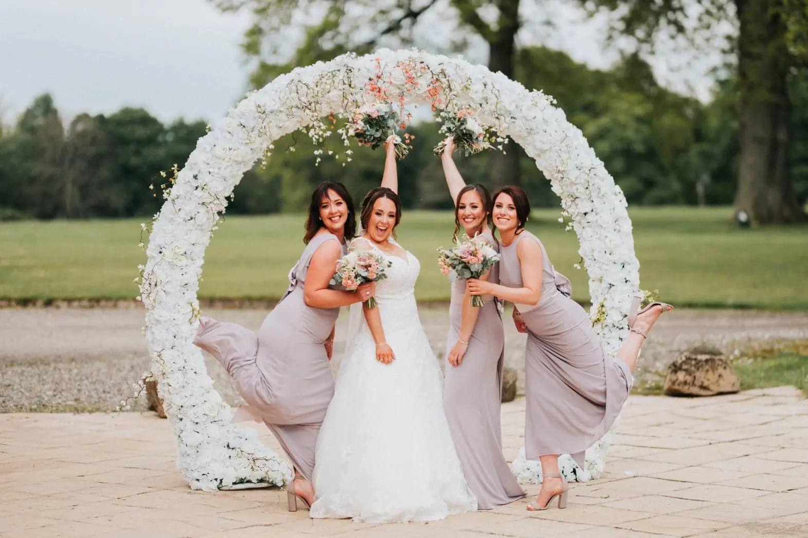 Happy wedding party photographed beneath an Instapic floral arch
