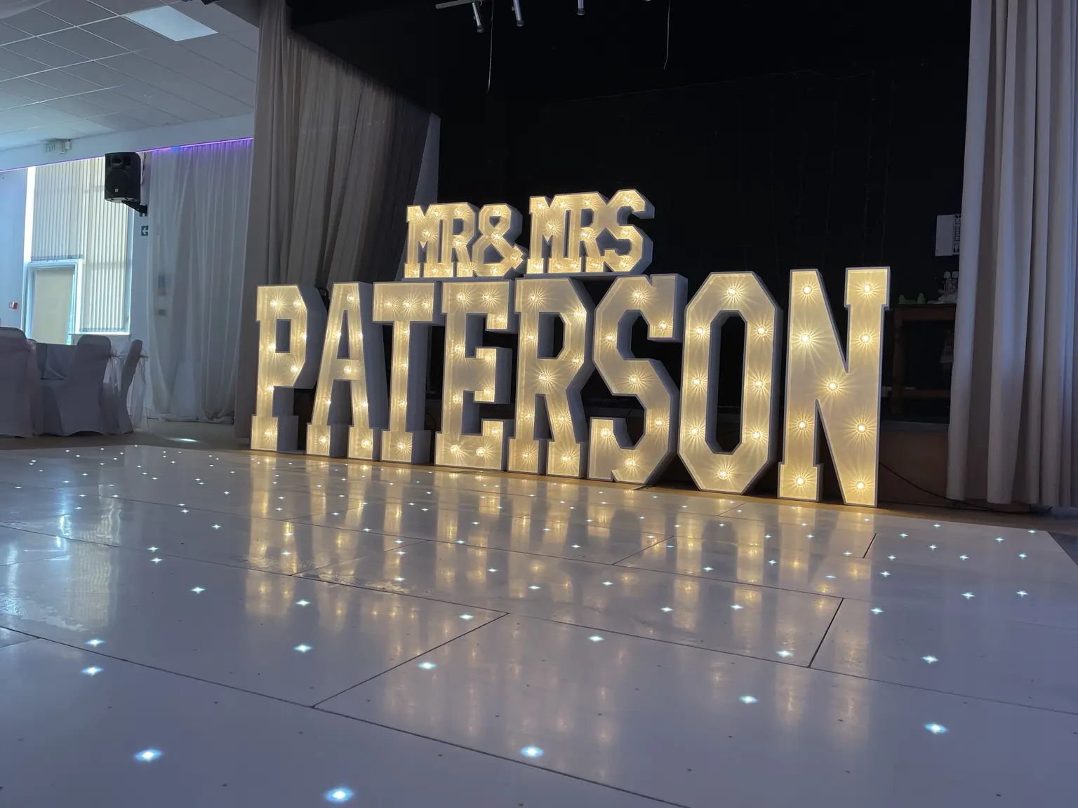 Personalised MR and MRS PATERSON light-up letters beside a white starlit dance floor