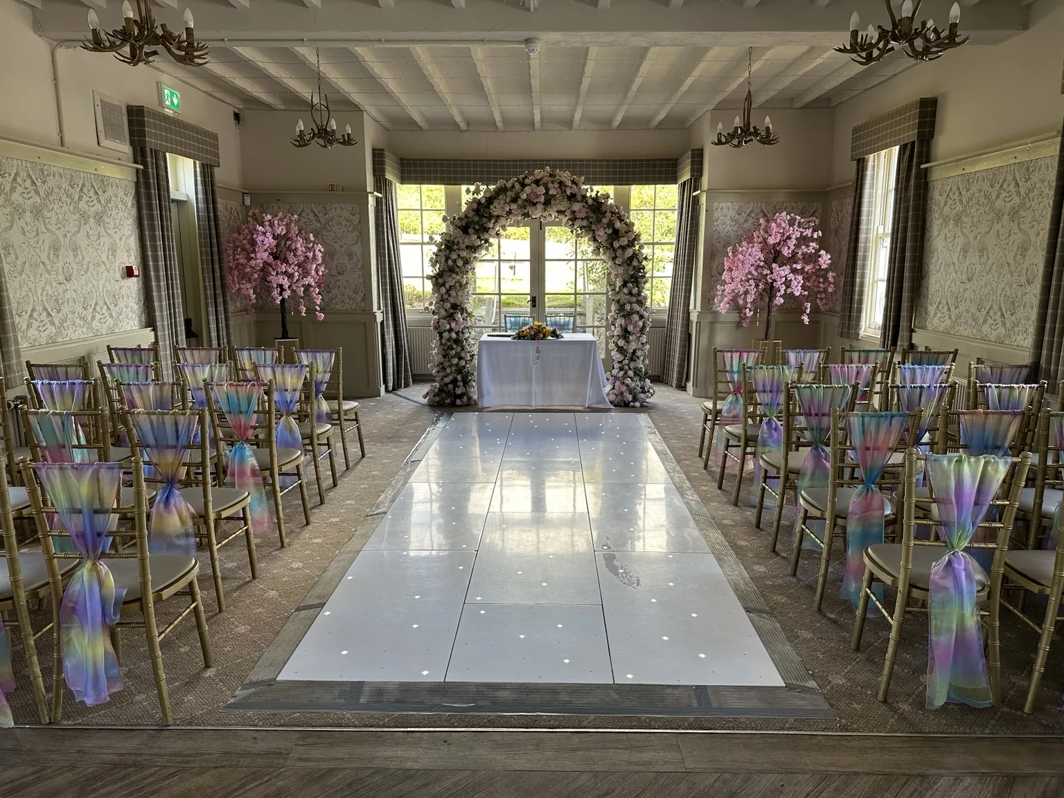 Blush floral arch at the end of a wedding aisle