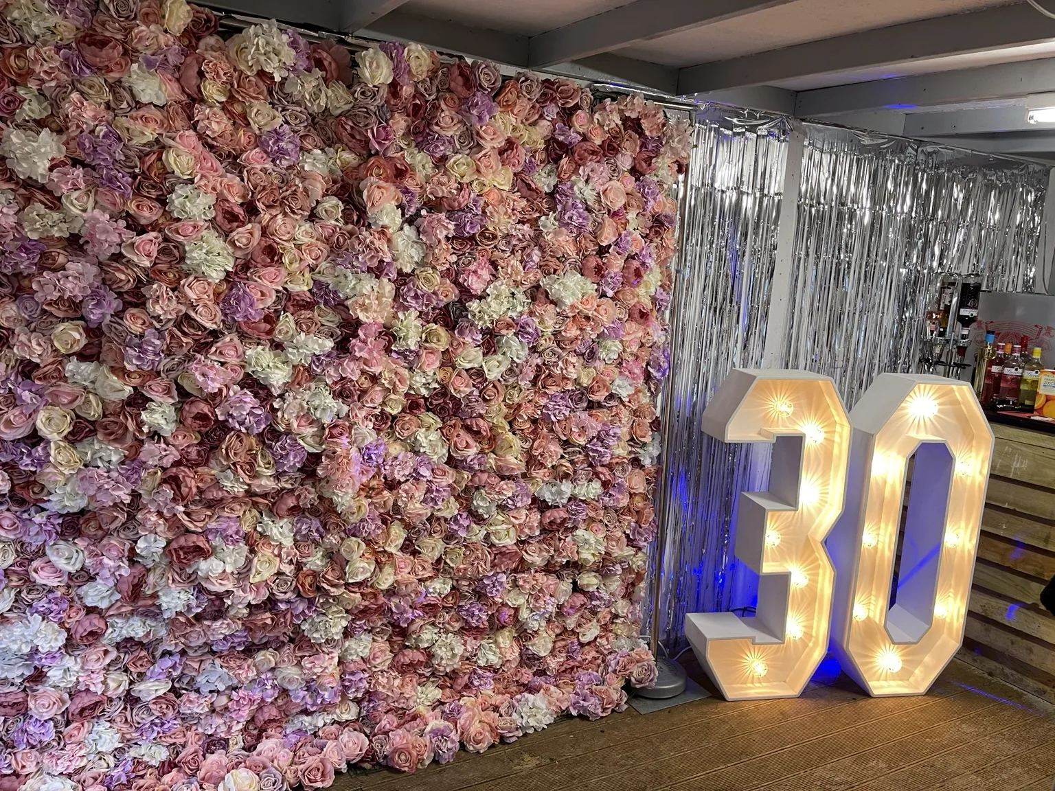 Pink flower wall styled beside illuminated 30 numbers